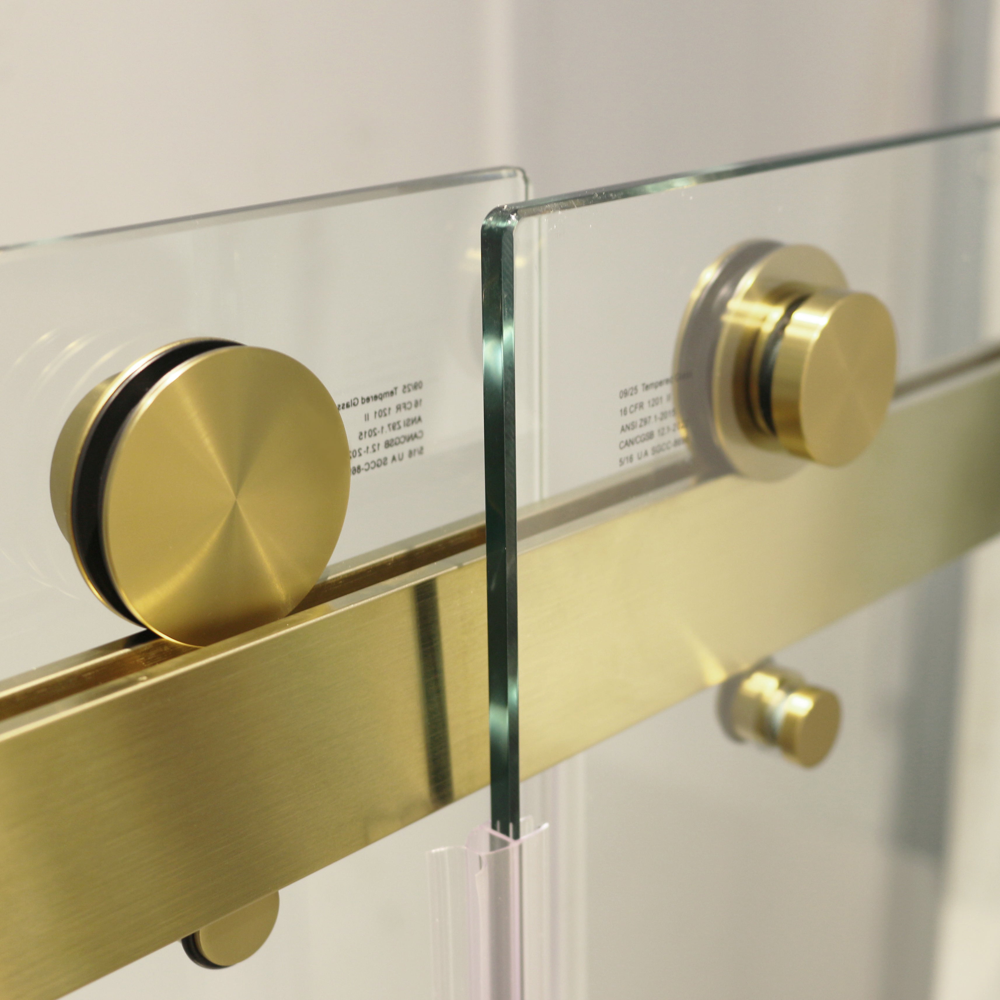 Frameless sliding shower door brushed gold roller track detail