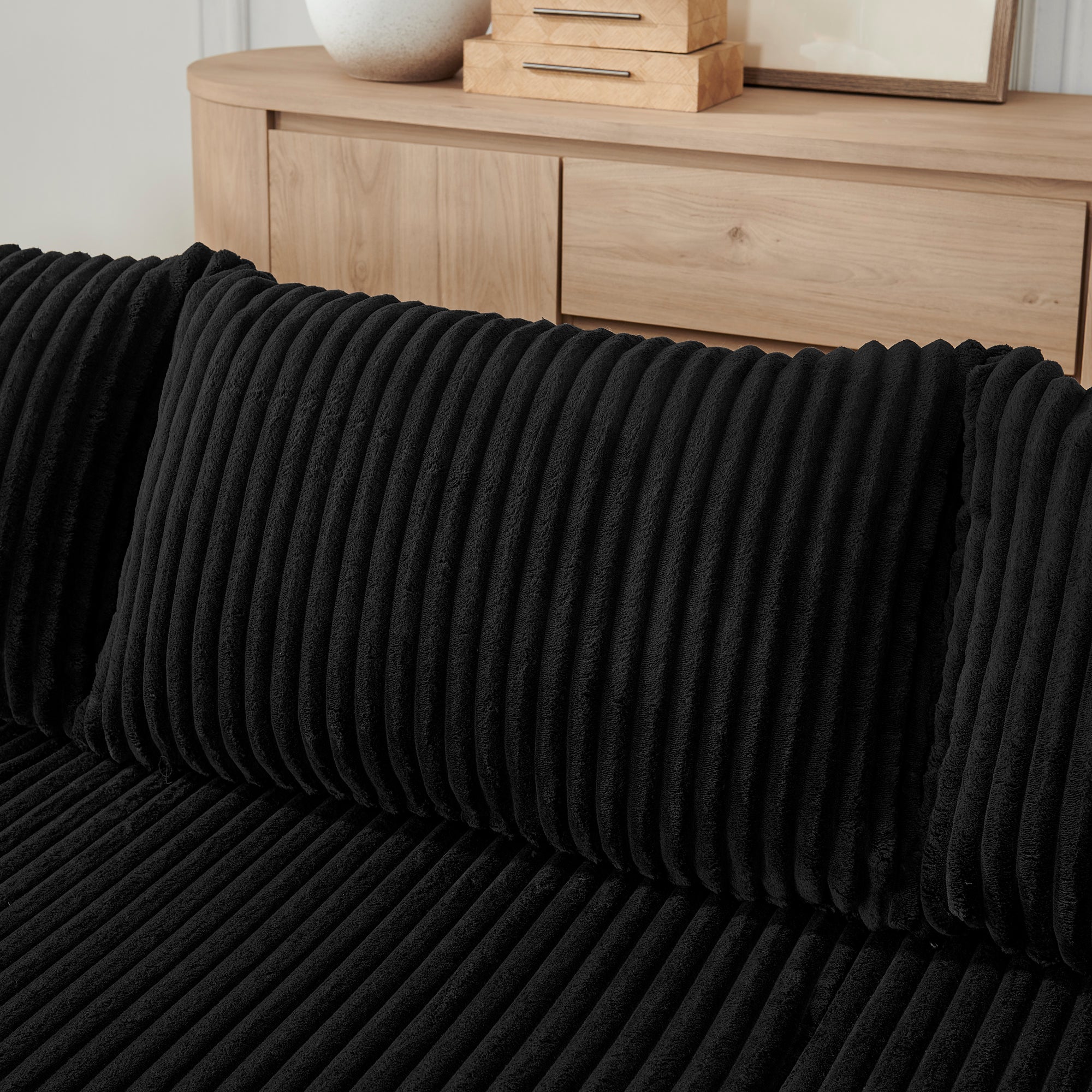 Compact black corduroy sectional sofa, seating detail view